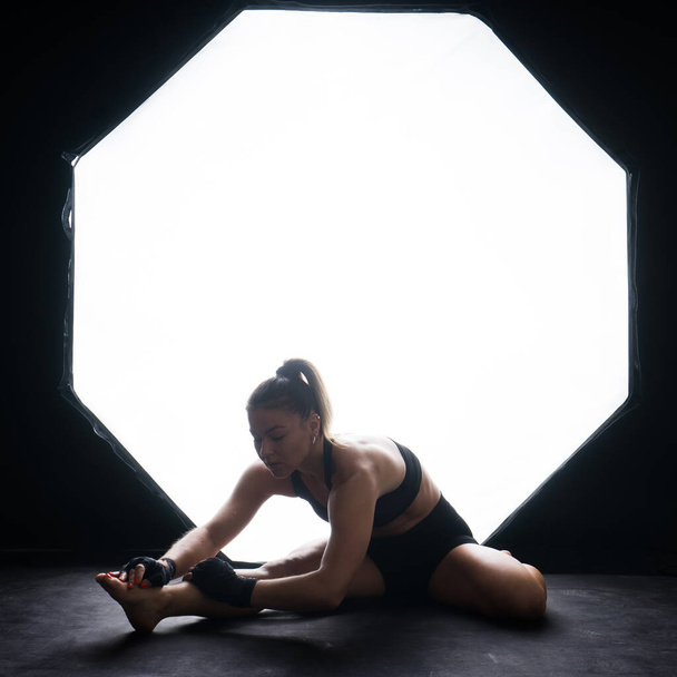 Fit lichaam. Jonge mooie vrouwelijke fitness trainer doet workout in de studio - Foto, afbeelding