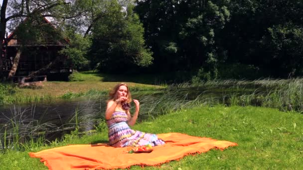 Zwangere vrouw zitten op tapijt, eten druif. Genoegens, zuivere lucht aard - Video