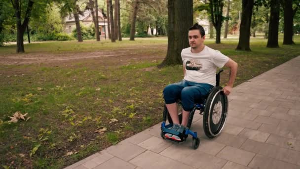 笑顔の幸せな男 都市公園で歩く車椅子に乗って 障害のないアクティブなライフスタイルモビリティ - 映像、動画