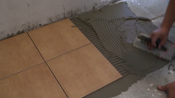 Ręka mistrza stawia dachówka cement kleju na podłodze. Remont domu - Materiał filmowy, wideo