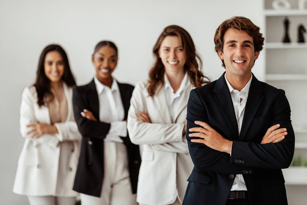 Male leadership concept. Diverse business team standing in line with folded arms and smiling at camera posing in office, selective focus on businessman - Photo, Image