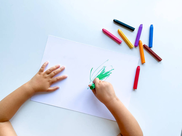 Küçük çocuk beyaz masaya pastel boya kalemleriyle resim çiziyor. Yüksek kalite fotoğraf - Fotoğraf, Görsel