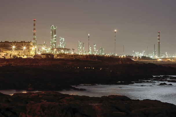 Нефтеперерабатывающий завод у моря ночью - Фото, изображение