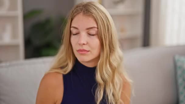Junge blonde Frau sitzt zu Hause auf Sofa und hustet - Filmmaterial, Video