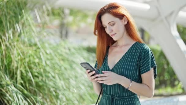 Young redhead woman smiling confident talking on the smartphone at park - Metraje, vídeo