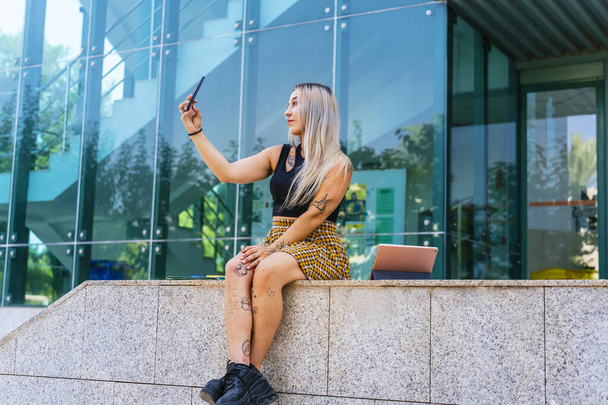Σύγχρονη φοιτήτρια που βγάζει φωτογραφία με το τηλέφωνό της στη Φιλοσοφική Σχολή. - Φωτογραφία, εικόνα