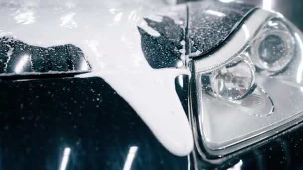 Πλύσιμο αυτοκινήτου close-up του εμπρός προφυλακτήρα προβολέα και πλέγμα ενός μαύρου αυτοκινήτου πολυτελείας μετά από λεπτομερή στοιχεία στο χώρο στάθμευσης ή το κέντρο εξυπηρέτησης αυτοκινήτων - Πλάνα, βίντεο