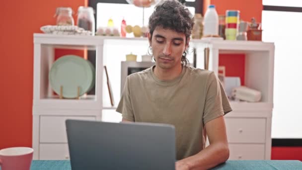 Young hispanic man using laptop sneezing at dinning room - Footage, Video