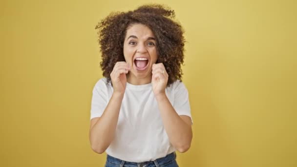 Young beautiful hispanic woman standing with surprise expression screaming over isolated yellow background - Footage, Video