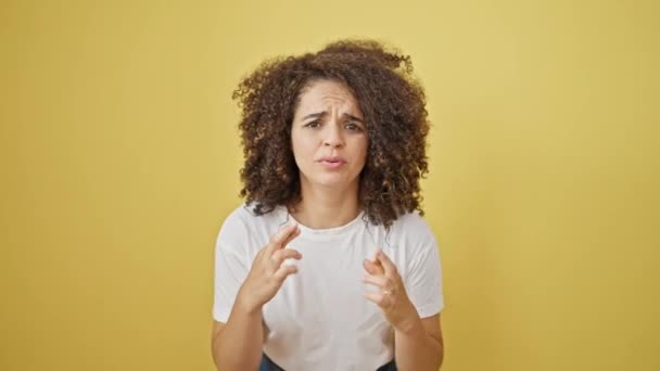 Young beautiful hispanic woman crossing fingers standing with winner gesture over isolated yellow background - Footage, Video