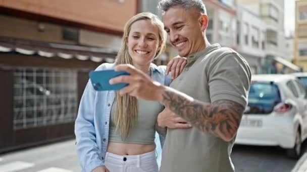 Hombre y mujer pareja viendo vídeo en smartphone riendo mucho en la calle - Imágenes, Vídeo