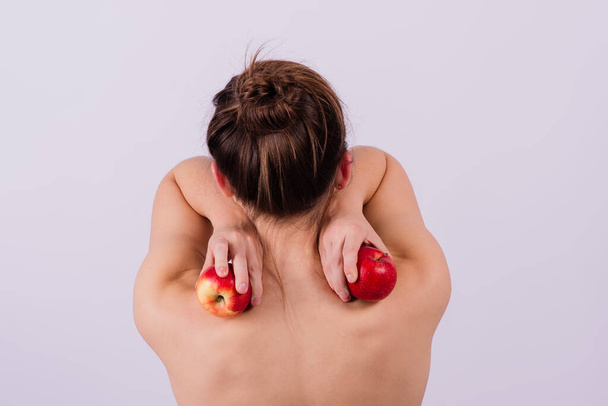 Hermosa mujer desnuda con manzanas mirando a la cámara, con las manos abiertas - Foto, imagen