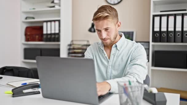 Молодий кавказький чоловік бізнесмен використовує ноутбук, що працює з виразом переможця в офісі - Кадри, відео