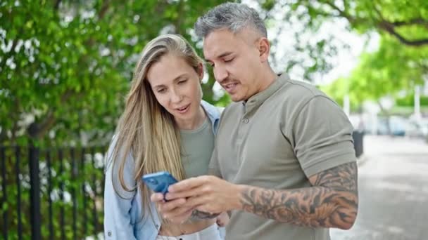 Man and woman couple smiling confident using smartphone at park - Filmmaterial, Video