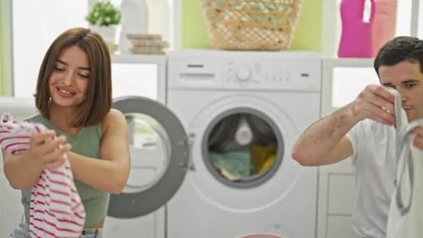 Gyönyörű pár mosolyog magabiztos mosás ruhák a mosókonyhában - Felvétel, videó