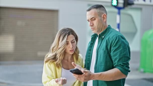 Άντρας και γυναίκα ζευγάρι που χρησιμοποιούν smartphone υποστηρίζοντας στο δρόμο - Πλάνα, βίντεο