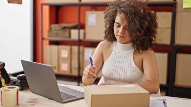 Fiatal gyönyörű spanyol nő e-kereskedelmi üzletember segítségével laptop írás a csomagot az irodában - Felvétel, videó