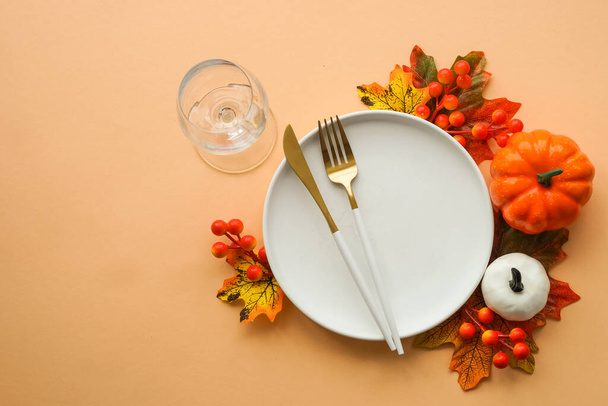Nastavení podzimního stolu. Bílý talíř, zlaté příbory a podzimní dekorace na oranžovém pozadí. Plochý obrázek s kopírovacím prostorem. - Fotografie, Obrázek