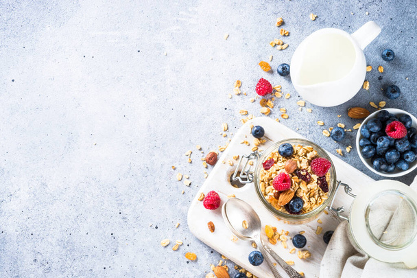 Granola friss bogyókkal és tejjel. Sült zabpehely Egészséges reggeli vagy desszert könnyű kő asztalnál. Felülnézet másolási hellyel. - Fotó, kép