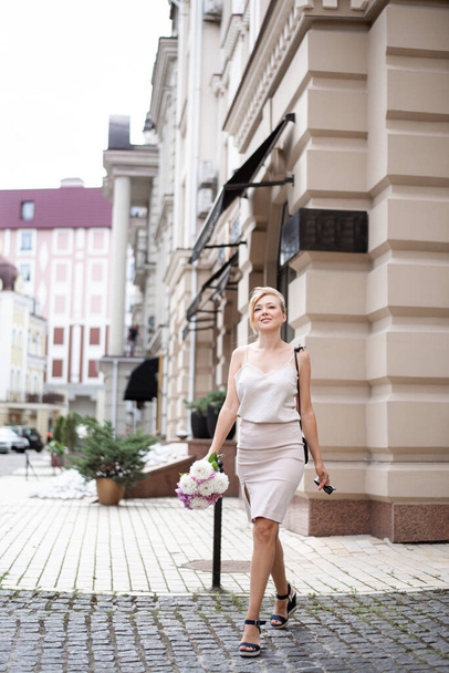 Mladý úspěšný dívka na ulici města s květinami chůze jde do kamery - Fotografie, Obrázek