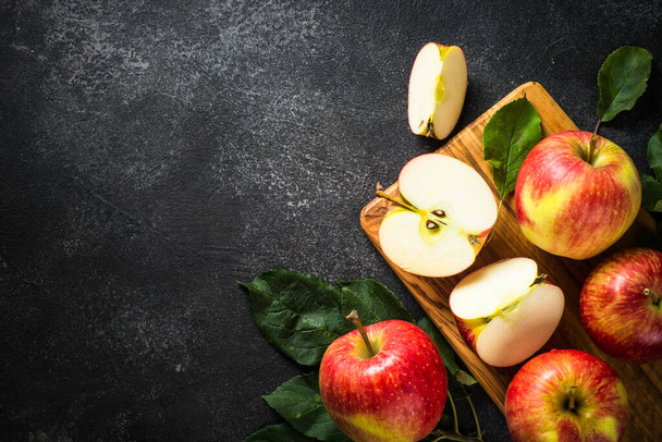 Manzanas frescas maduras, manzanas enteras y cortadas en rodajas en la mesa de piedra negra. Vista superior con espacio de copia. - Foto, Imagen