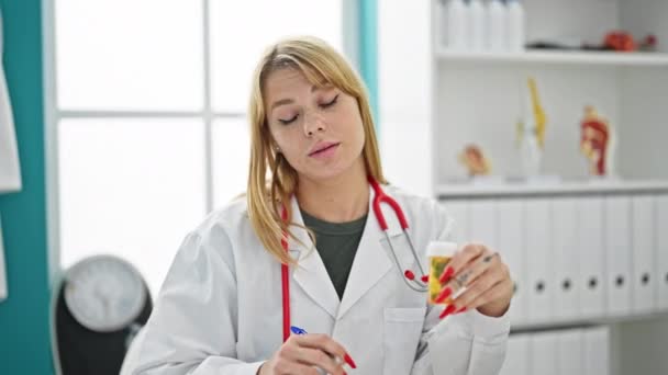 若い金髪女性医師は,クリニックで話す錠剤を処方します - 映像、動画