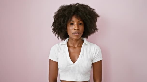 donna afroamericana in piedi con espressione seria dicendo di no con il dito su sfondo rosa isolato - Filmati, video