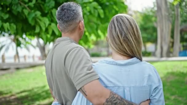 Hombre y mujer pareja abrazándose de pie hacia atrás en el parque - Metraje, vídeo
