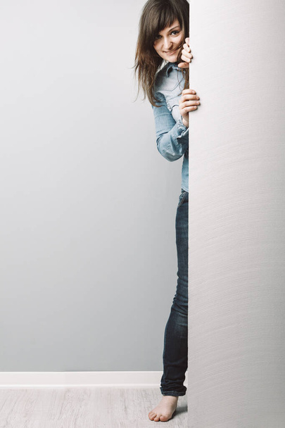 ciekawska młoda kobieta w jeansowej koszuli, z długimi włosami, rówieśnicy zza niebieskotonowego COPYSPACE, zapraszając do przyłączenia się do jej zainteresowania - Zdjęcie, obraz
