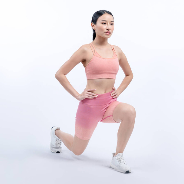 Giovane donna asiatica attraente in abbigliamento sportivo che si estende prima di routine di esercizio di fitness. Allenamento sano per la cura del corpo con donna atletica che si riscalda su uno sfondo isolato. Vigoroso - Foto, immagini