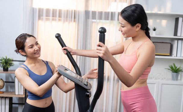 Energetikus és erős sportos ázsiai nő fut elliptikus futógépen otthon edzés haver vagy edző. Az egészséges fizikum és az egészséges életmód iránti elkötelezettség. Élénk. - Fotó, kép