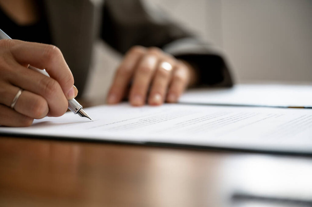 Visão aproximada de baixo ângulo de mãos femininas, advogado, agente de seguros ou empresária, assinando um documento ou contrato com uma caneta de tinta. - Foto, Imagem