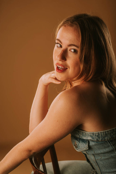 close-up van een meisje glimlachen terwijl zitten op de stoel in de studio - Foto, afbeelding