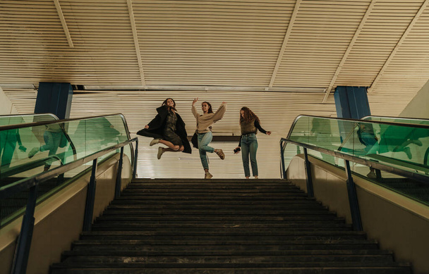 Hermosas chicas felices están saltando antes de ir abajo en el centro comercial - Foto, imagen