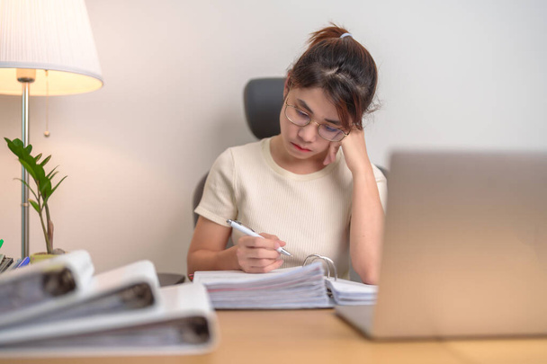 азиатка, использующая ноутбук, уставшая деловая женщина, работающая с головной болью и сонливая в офисе, измученная случайная женщина с компьютером поздно ночью дома. Концепция трудовой жизни - Фото, изображение