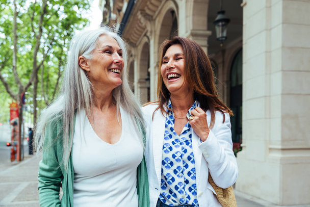 Beautiful senior women bonding outdoors in the city - Attractive cheerful mature female friends having fun, shopping and bonding, concepts about elderly lifestyle - Foto, afbeelding
