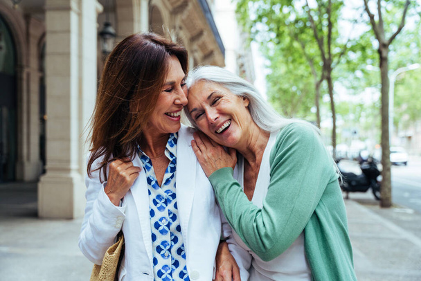 Mooie oudere vrouwen bindingen buiten in de stad - Aantrekkelijke vrolijke volwassen vrouwelijke vrienden hebben plezier, winkelen en binding, concepten over oudere levensstijl - Foto, afbeelding