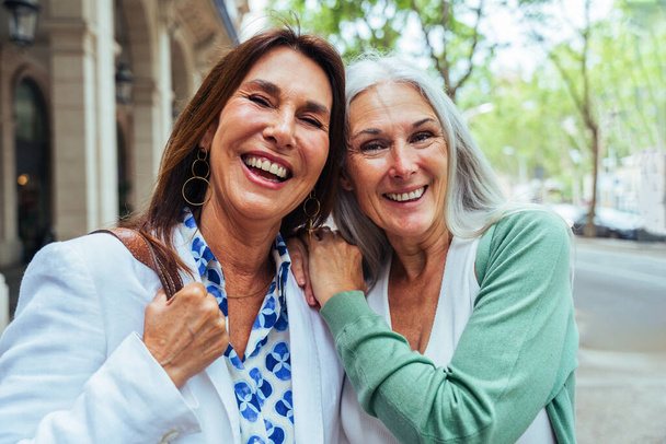 Beautiful senior women bonding outdoors in the city - Attractive cheerful mature female friends having fun, shopping and bonding, concepts about elderly lifestyle - Photo, Image