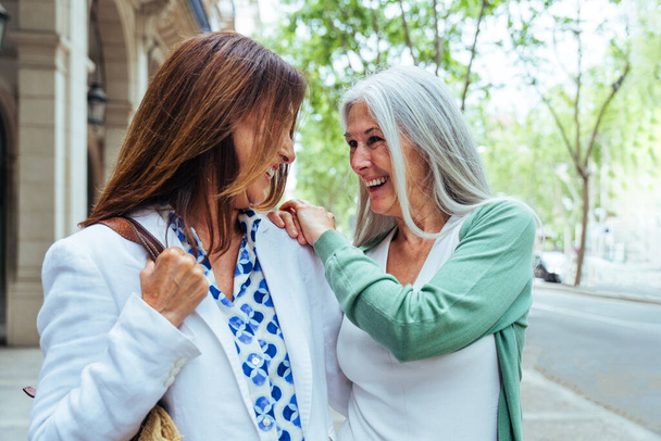 Beautiful senior women bonding outdoors in the city - Attractive cheerful mature female friends having fun, shopping and bonding, concepts about elderly lifestyle - Fotó, kép