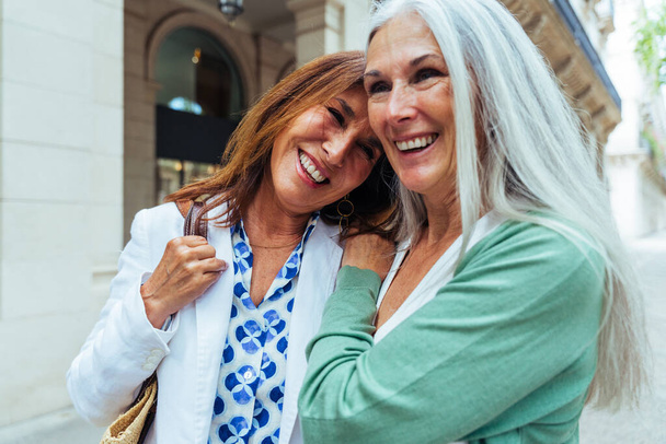 Beautiful senior women bonding outdoors in the city - Attractive cheerful mature female friends having fun, shopping and bonding, concepts about elderly lifestyle - Fotoğraf, Görsel