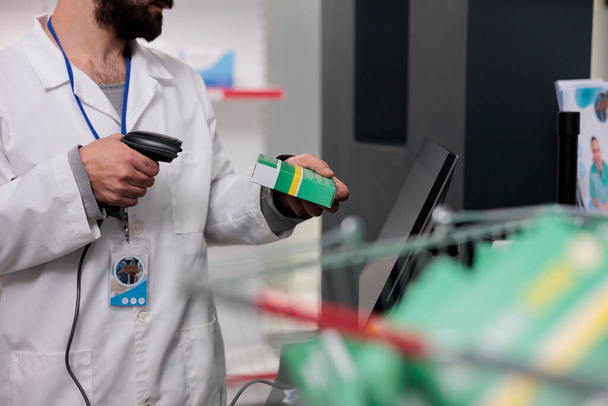 Чоловік фармацевт тримає сканер магазину, який читає штрих-коди на всіх ліках і пакетах, щоб забезпечити точність у дозуванні ліків. Працівник аптеки працює в аптеці, перевіряючи добавки - Фото, зображення