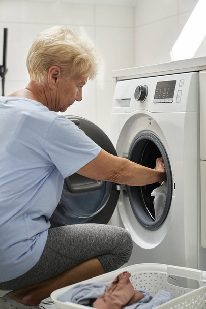 Senior woman loading a washing machine - Fotografie, Obrázek