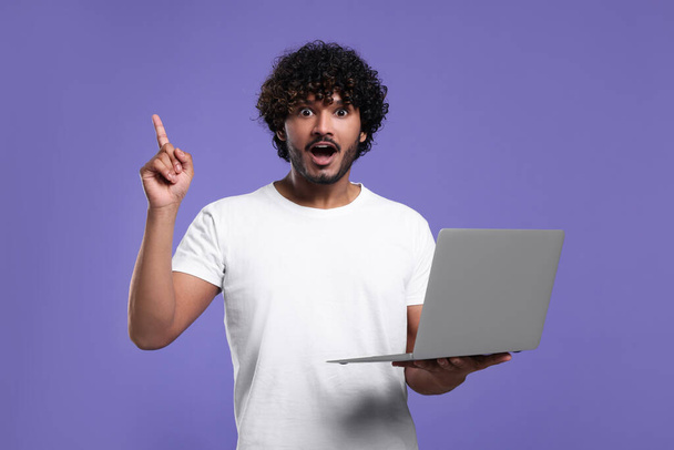 Surprised man with laptop on purple background - Photo, Image
