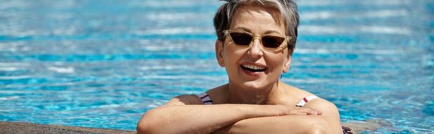 fröhliche Frau mittleren Alters in Sonnenbrille und Badeanzug im Schwimmbad, Rückzug, Banner - Foto, Bild