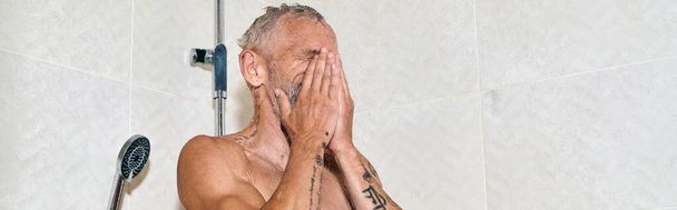 middle aged and shirtless man with tattoos taking shower and washing face, personal hygiene, banner - Photo, Image