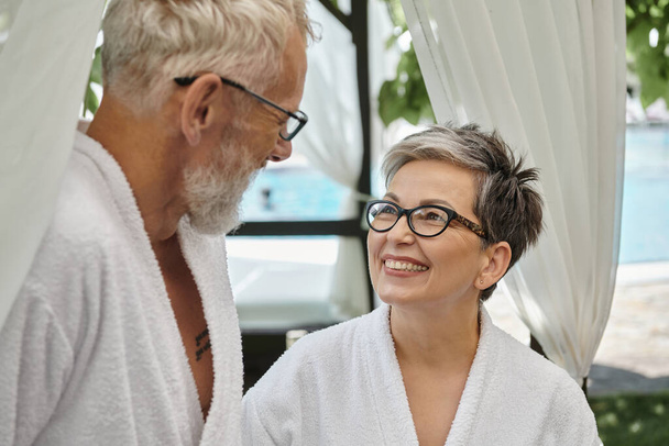 szczęśliwy w średnim wieku kobieta w okularach patrząc na męża w białej szacie, wellness rekolekcje koncepcja - Zdjęcie, obraz