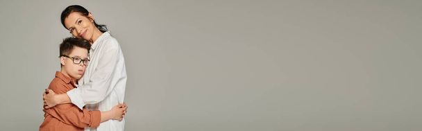 femme mature et garçon avec le syndrome du duvet dans des vêtements élégants embrassant gris, bonheur, bannière - Photo, image