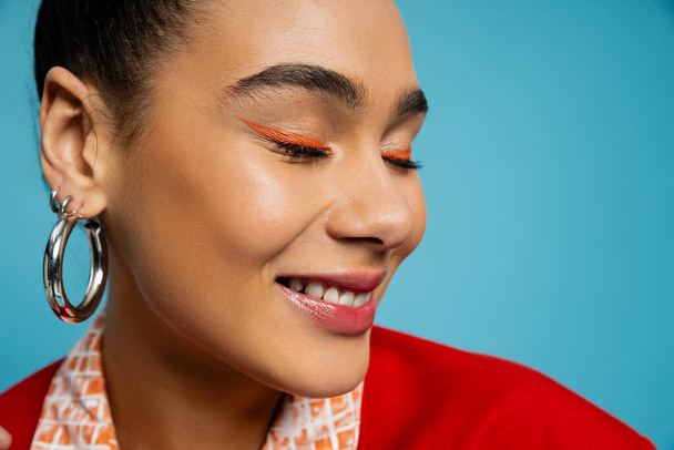 közeli-ból elégedett afro-amerikai modell ezüst kiegészítők mosolygós kék háttér - Fotó, kép