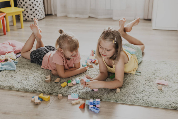 Діти грають з барвистими іграшками. Діти лежать на килимі вдома в спальні або дитячому садку, дитячій. Освітня екологічна гра для дітей. Ігровий час дозвілля, насолоджуючись сімейним спілкуванням - Фото, зображення