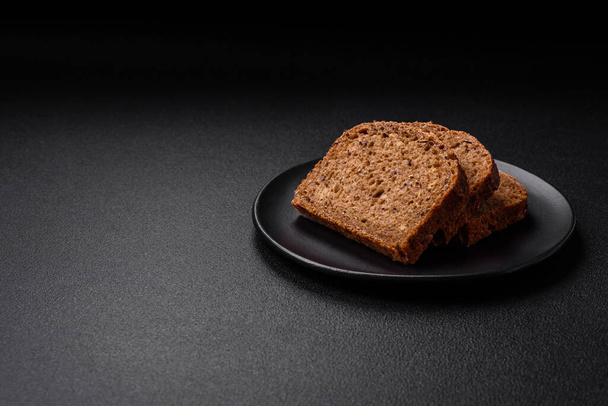Koyu beton arka planda tahıl ve çekirdekli lezzetli çıtır kahverengi ekmek. - Fotoğraf, Görsel
